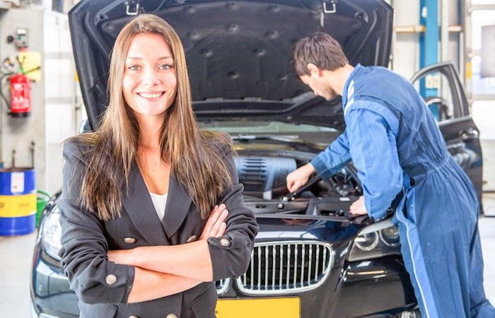 Klant in de werkplaats van ASC Grevelink in Vriezenveen terwijl een monteur aan haar auto werkt